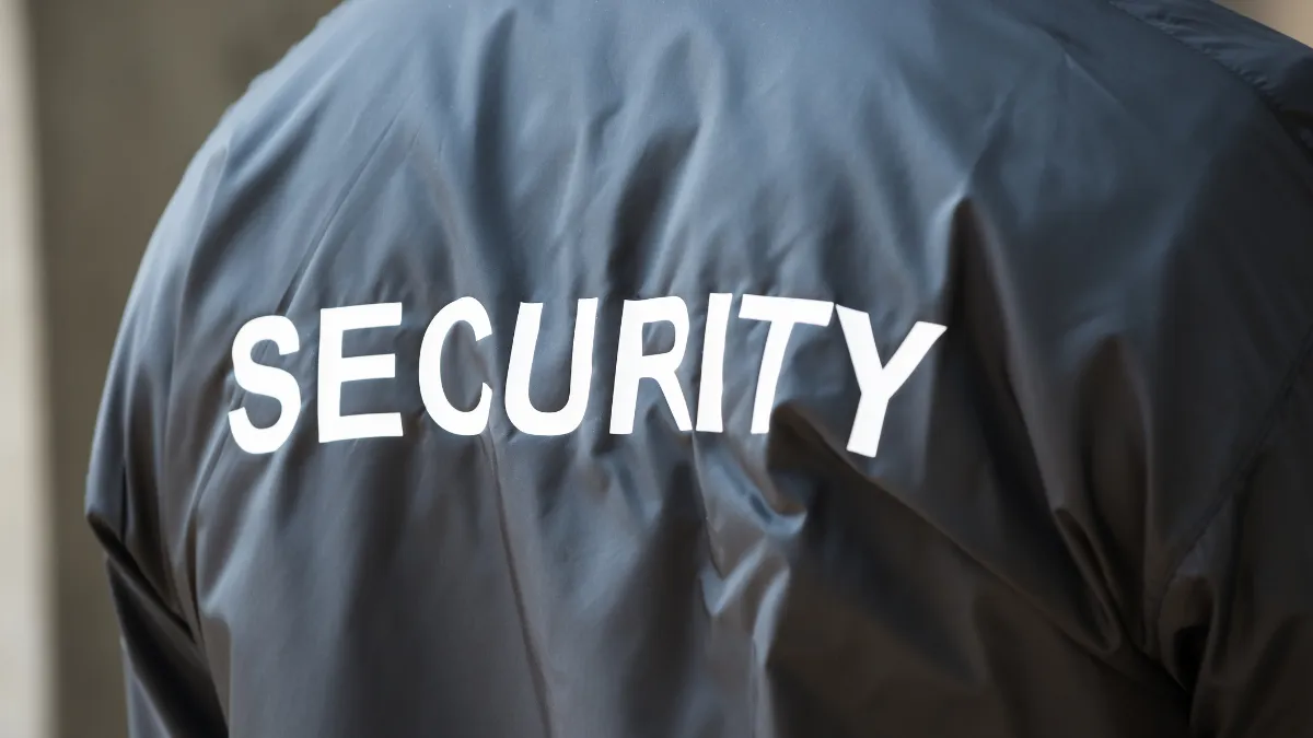 The back of a person wearing a dark jacket with SECURITY printed across it